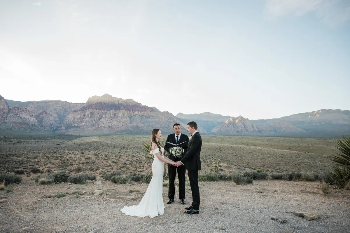 Bride and groom holding hands during an outdoor ceremony in the desert mountains for their Las Vegas wedding.