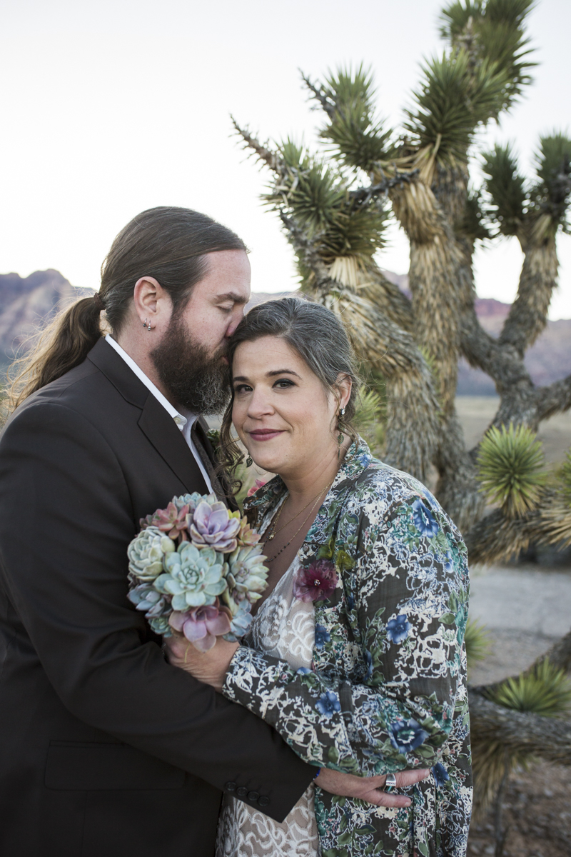 Groom kisses brides forehead.