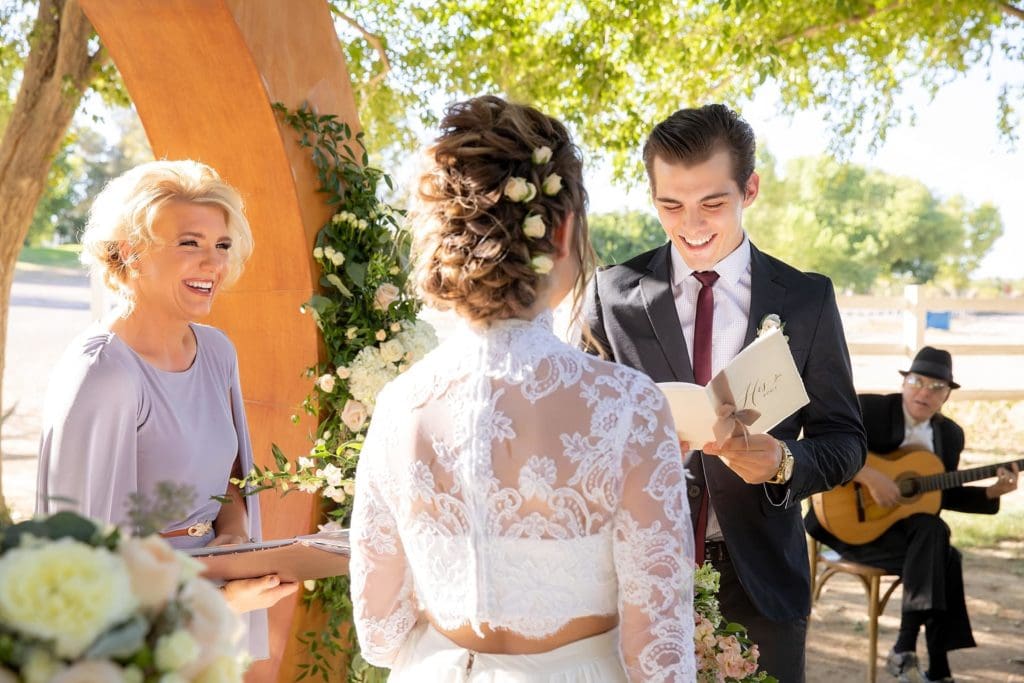 Groom reciting his vows to his bride while minister and wedding musician watch.