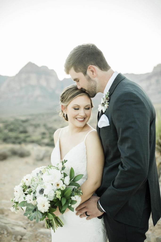 Man kisses woman on head with mountain backdrop