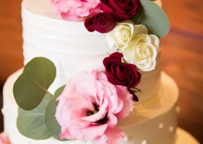 Wedding cake with pink, red and ivory flowers.