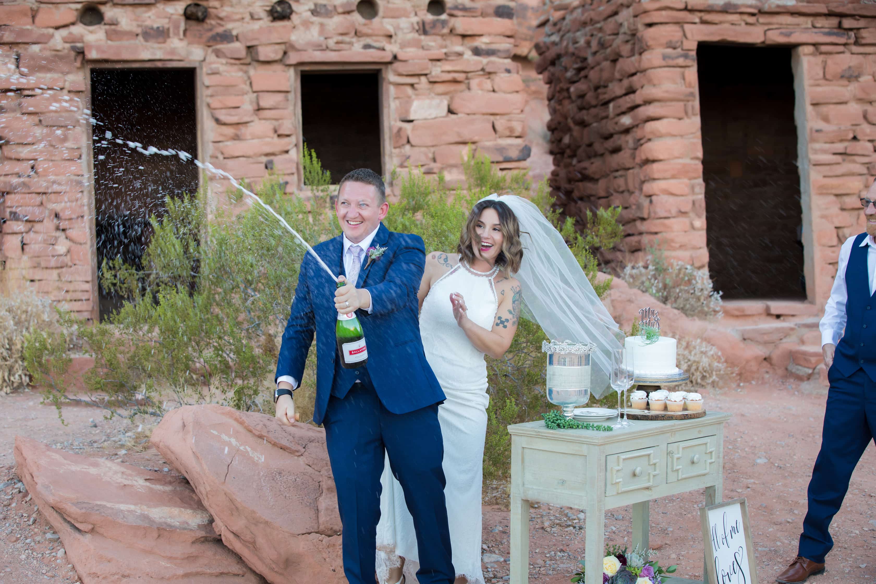 Bride and groom popping the top off a champagne bottle after eloping.