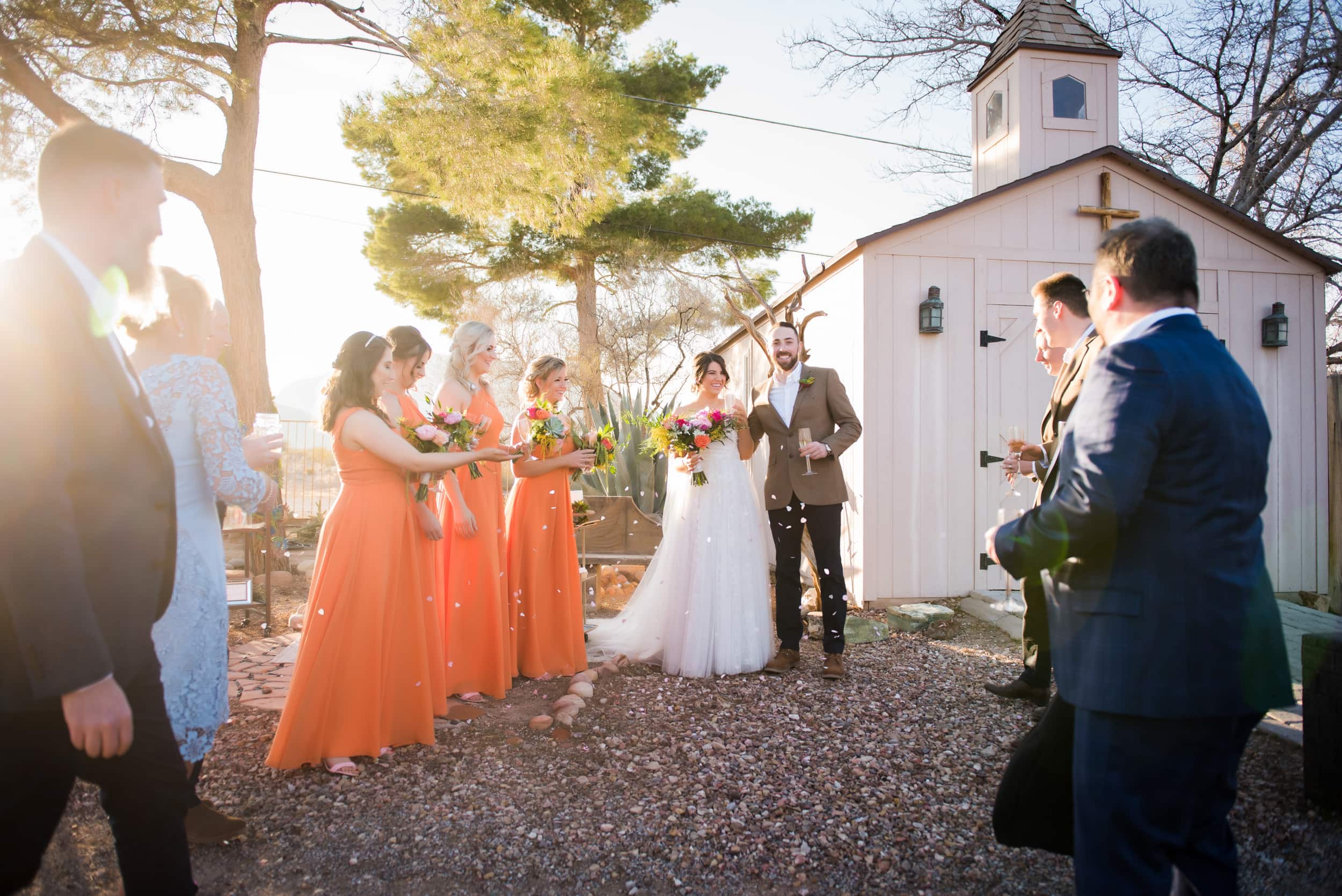 Bridal party in bright orange bridemaid dresses.