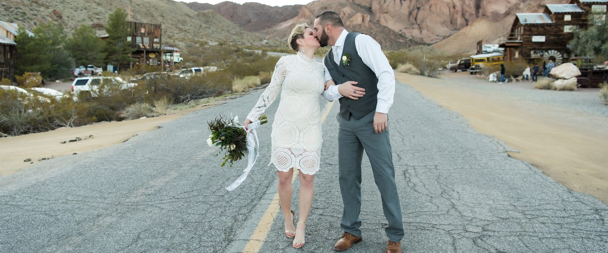 Bride and groom kissing in the middle of a deserted road.