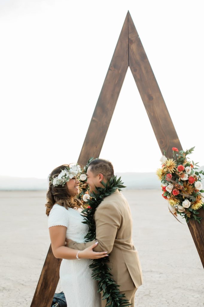 Kerrigan and Trevor kissing in front of their ceremony arbor.