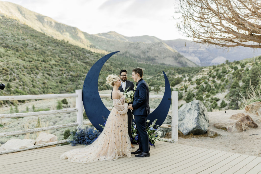 Ceremony couple standing in front of moon wedding decor.