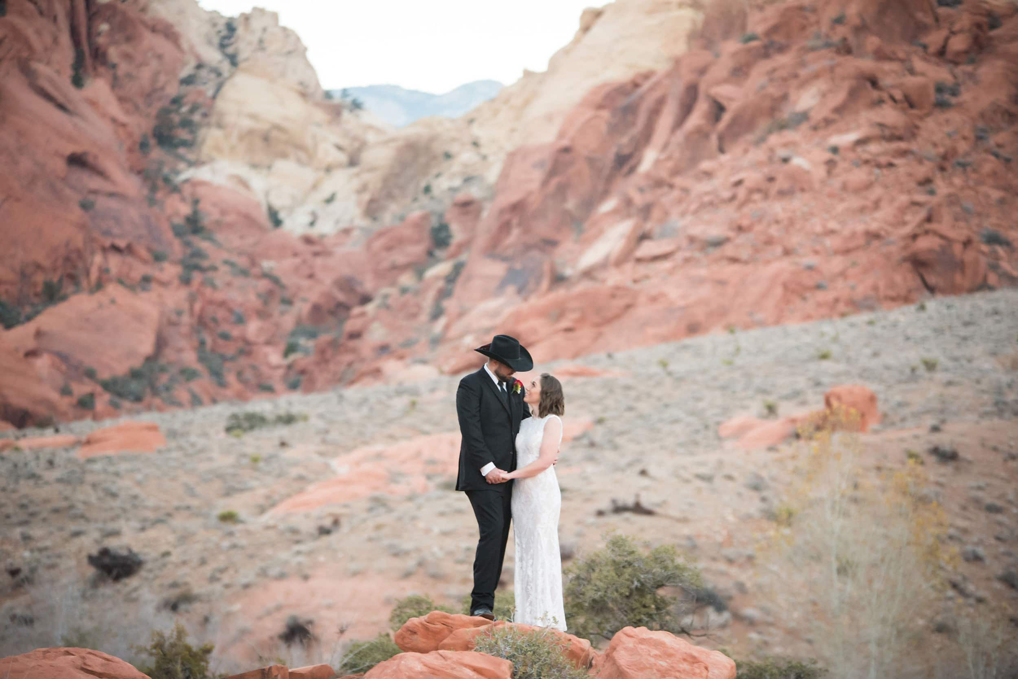 Bride and groom embracing each other in the middle of the desert at their western themed wedding.
