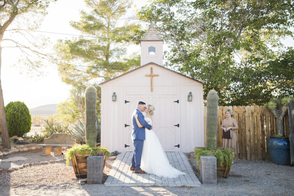 Newlywed couple kissing in front of outdoor chapel