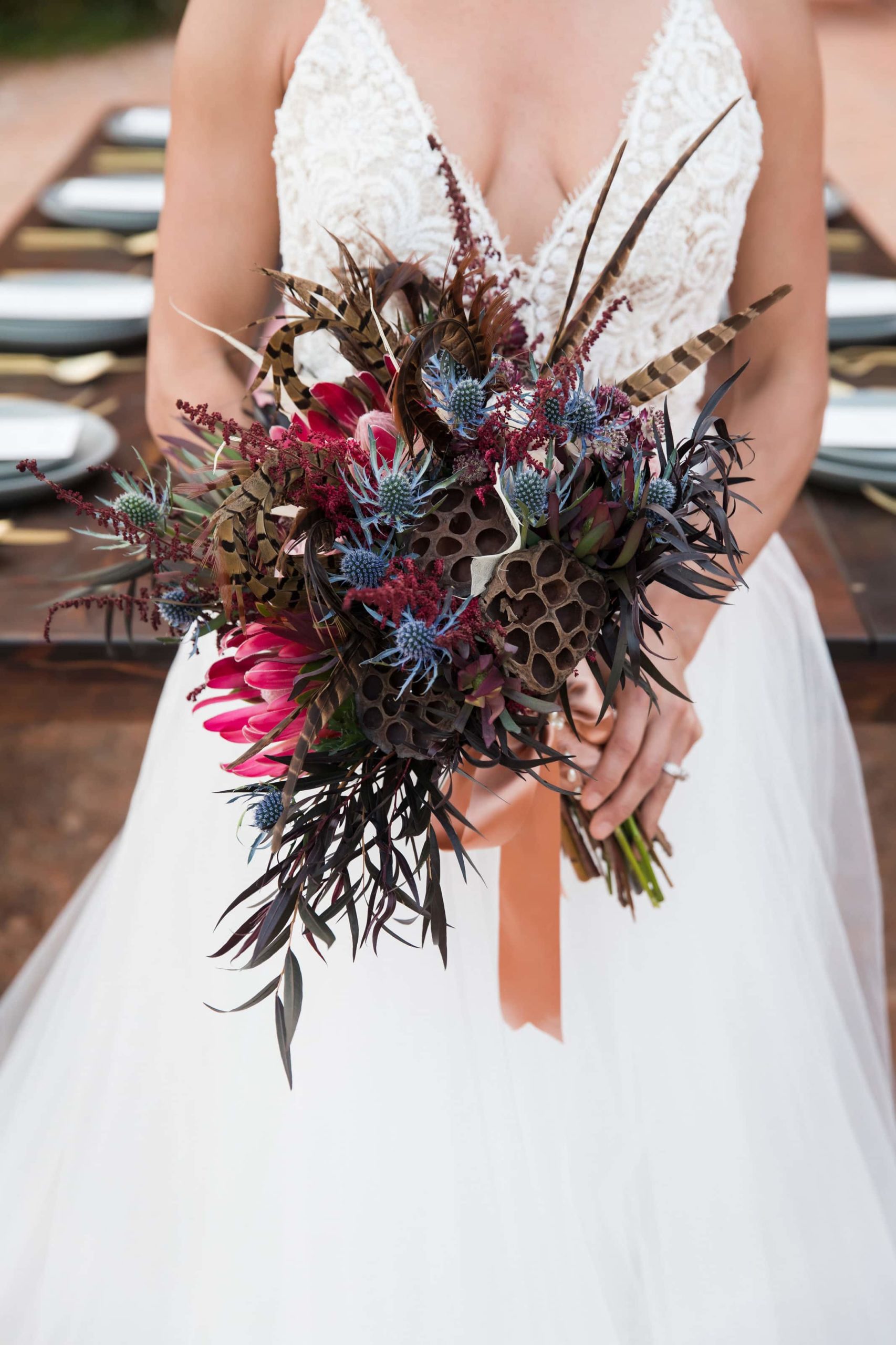 Bride in white dress holding a bouquet of flowers with a western theme.