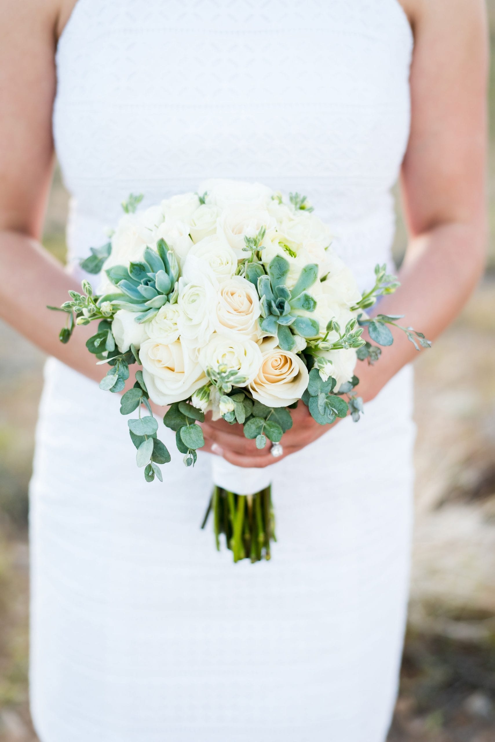 Bride in white wedding gown holding a small, white bouquet of flowers.