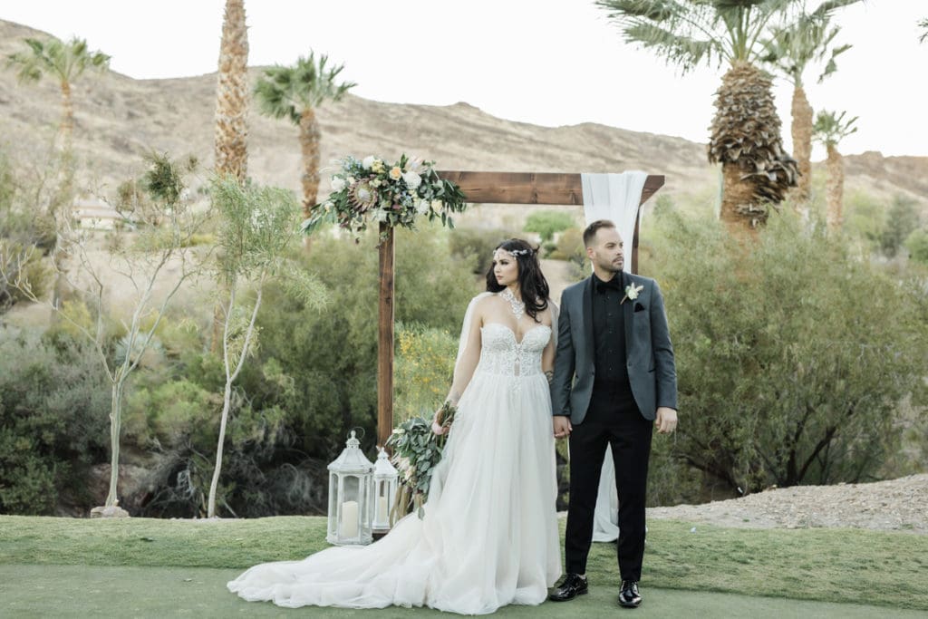Couple at ceremony in front of rectagular arbor