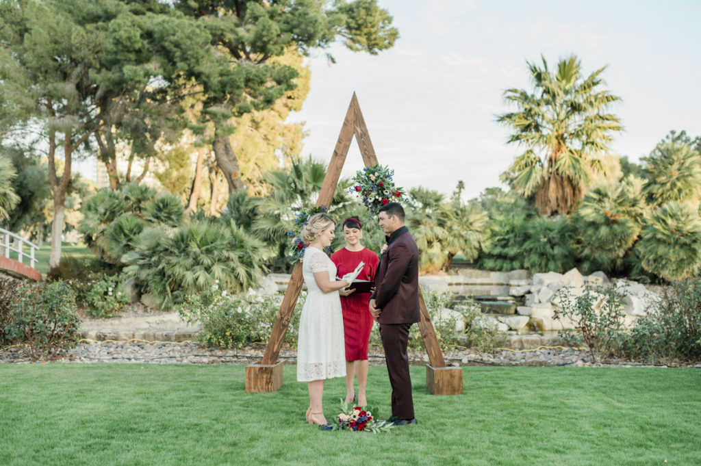 Couple at ceremony in front of triangular arbor