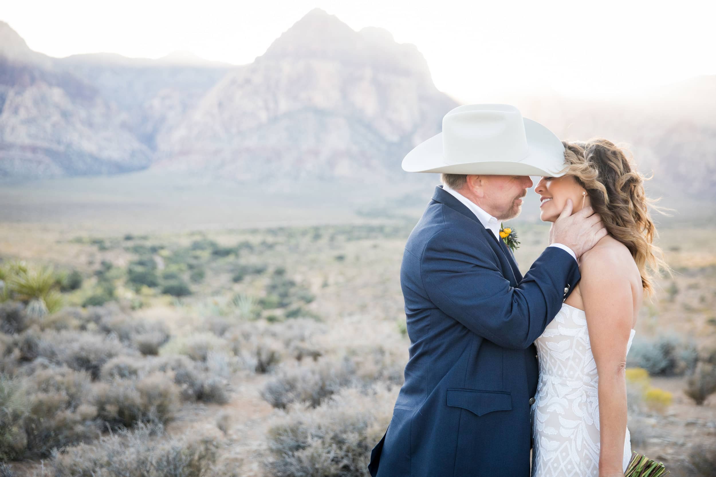 Groom cradling his bride's head in his hands as they begin to kiss.