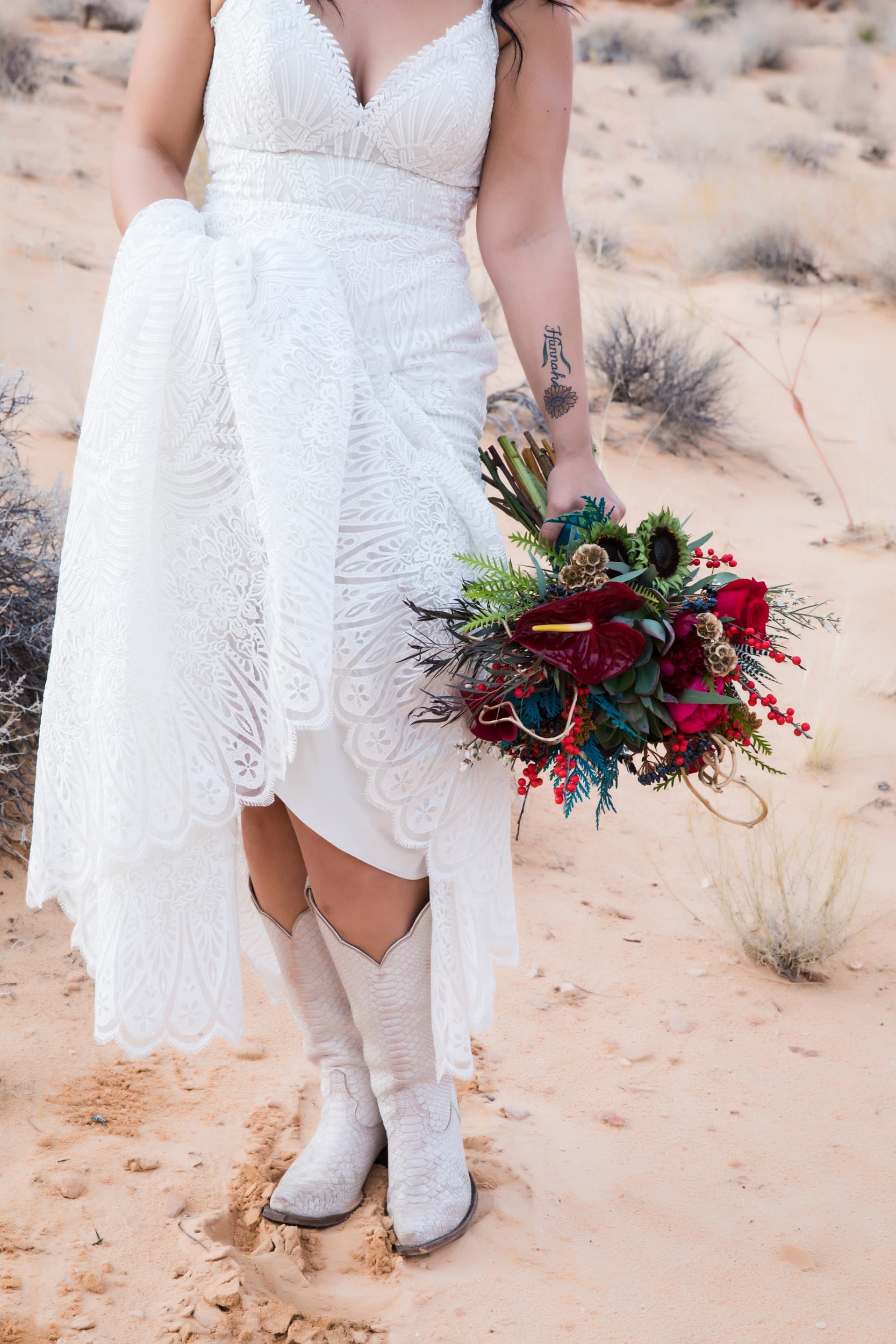 Woman in white wedding dress and white western boots holding a wedding bouquet.