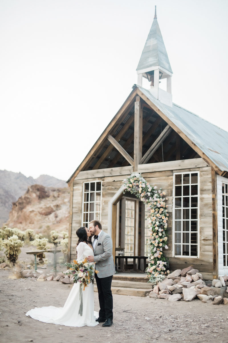 Groom and bride sharing a kiss in front of the Eldorado Canyon outdoor chapel in Las Vegas.