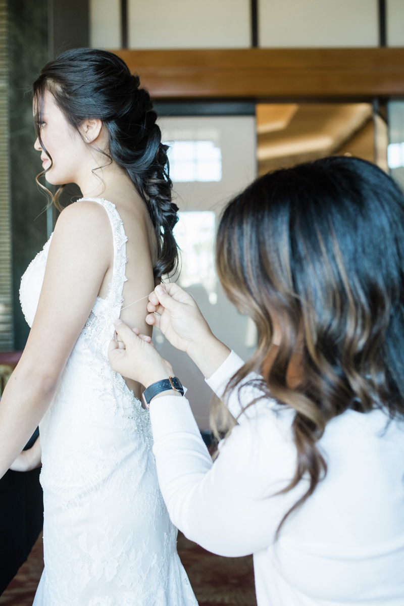 Wedding planner assisting bride with gown alteration.