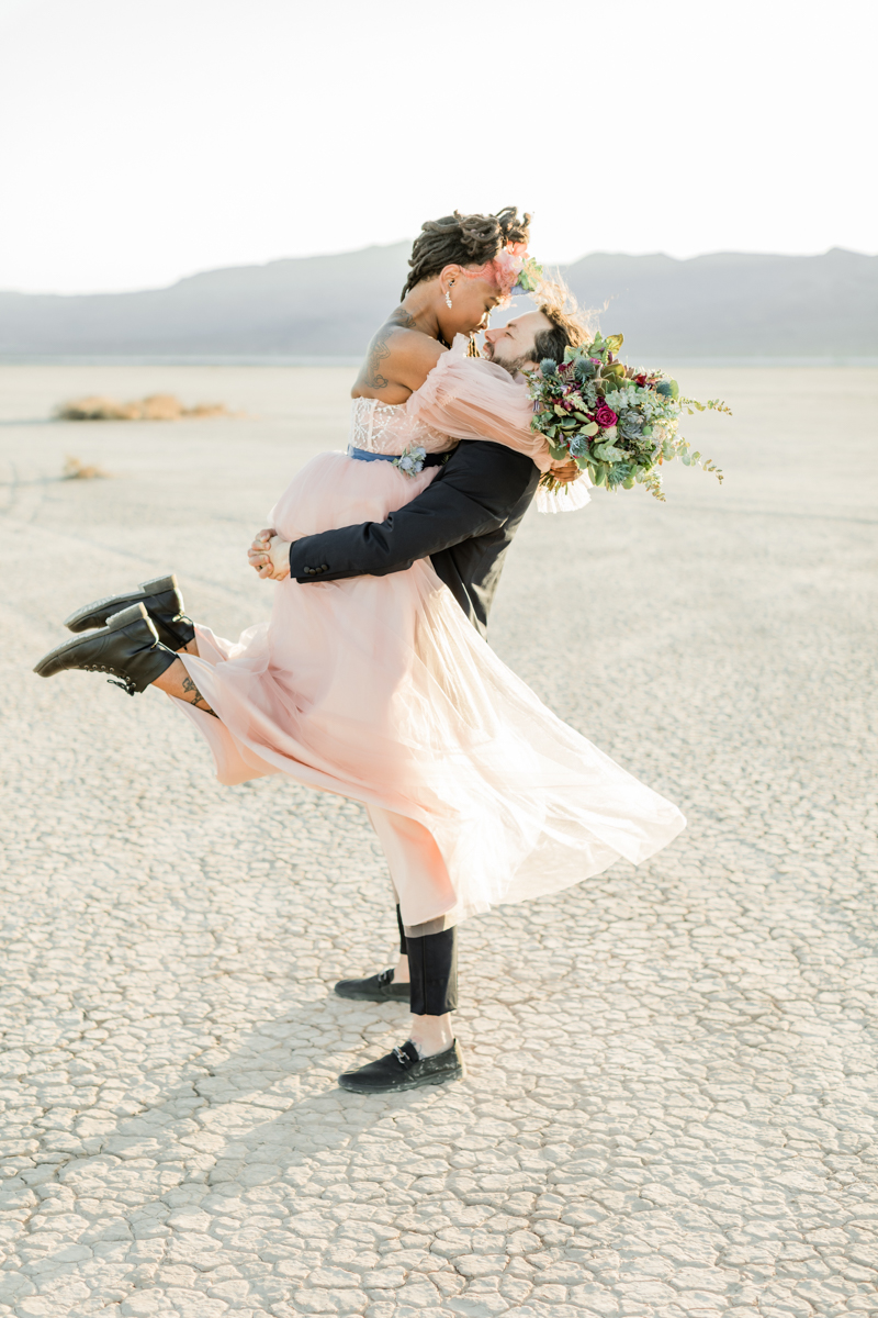 bride lifting groom in desert
