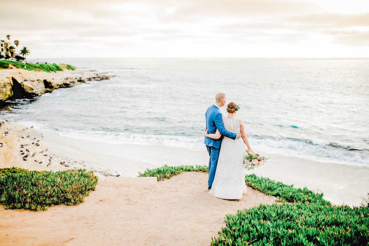bride and groom in sand overlooking ocean in san diego