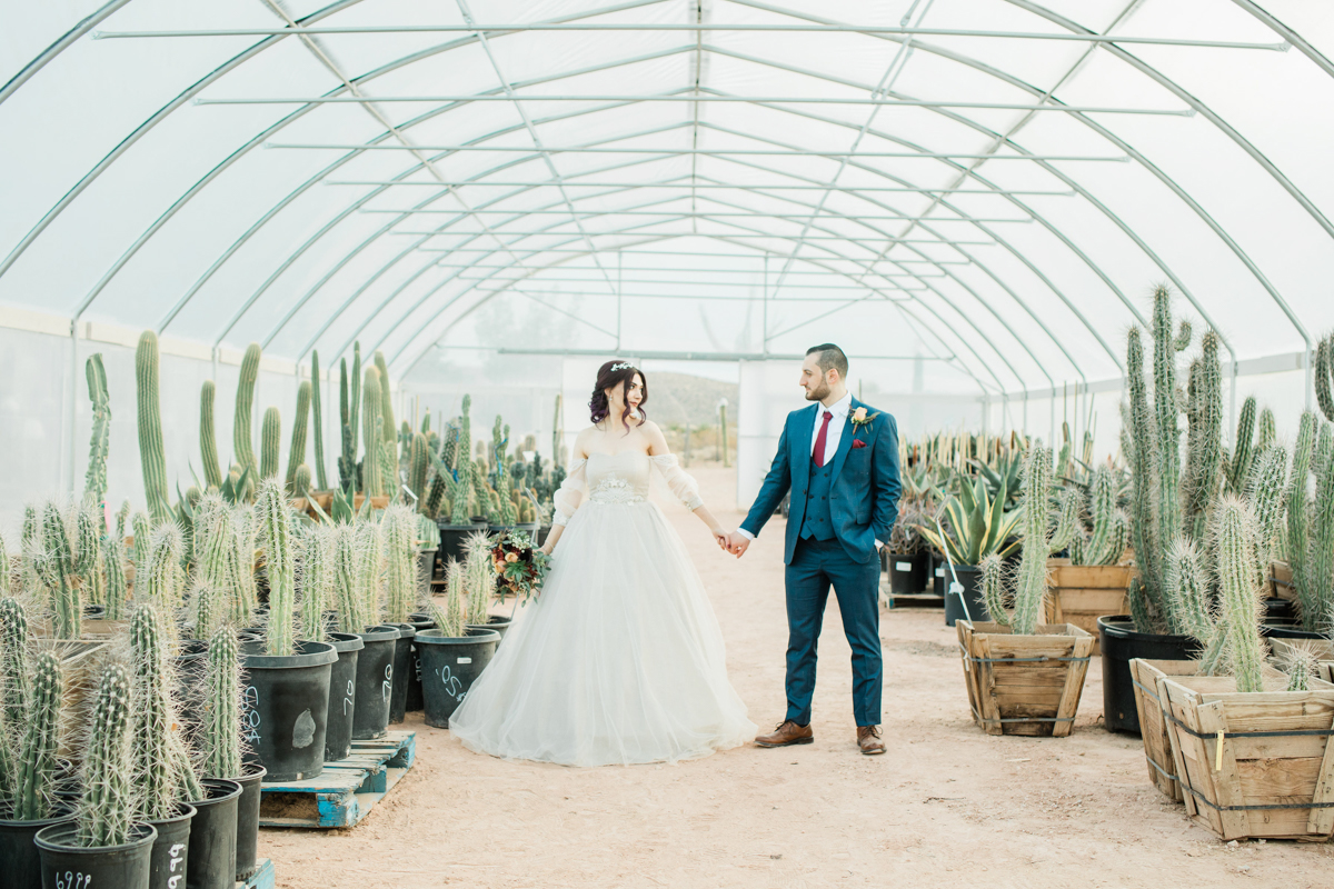 bride and groom holding hands in a cactus greenhouse