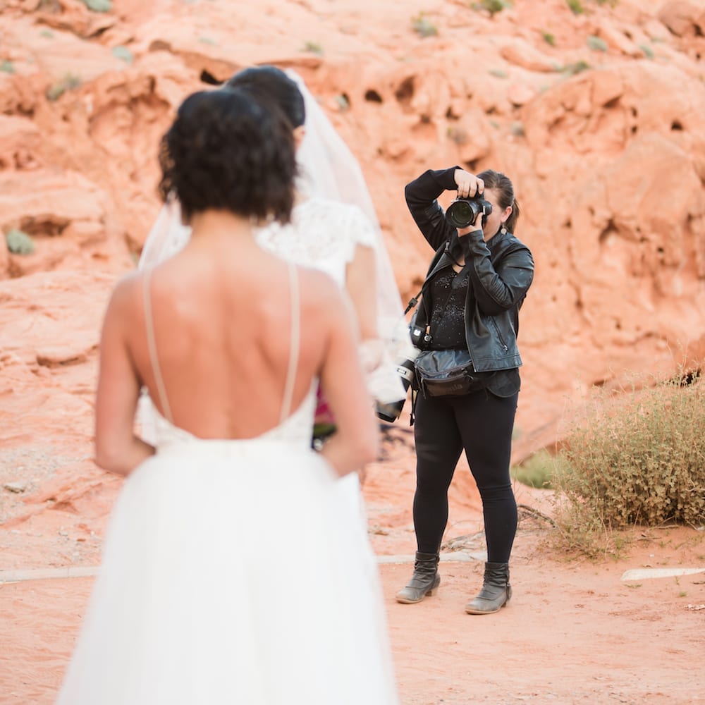 Photographer taking pics of two brides in the desert.